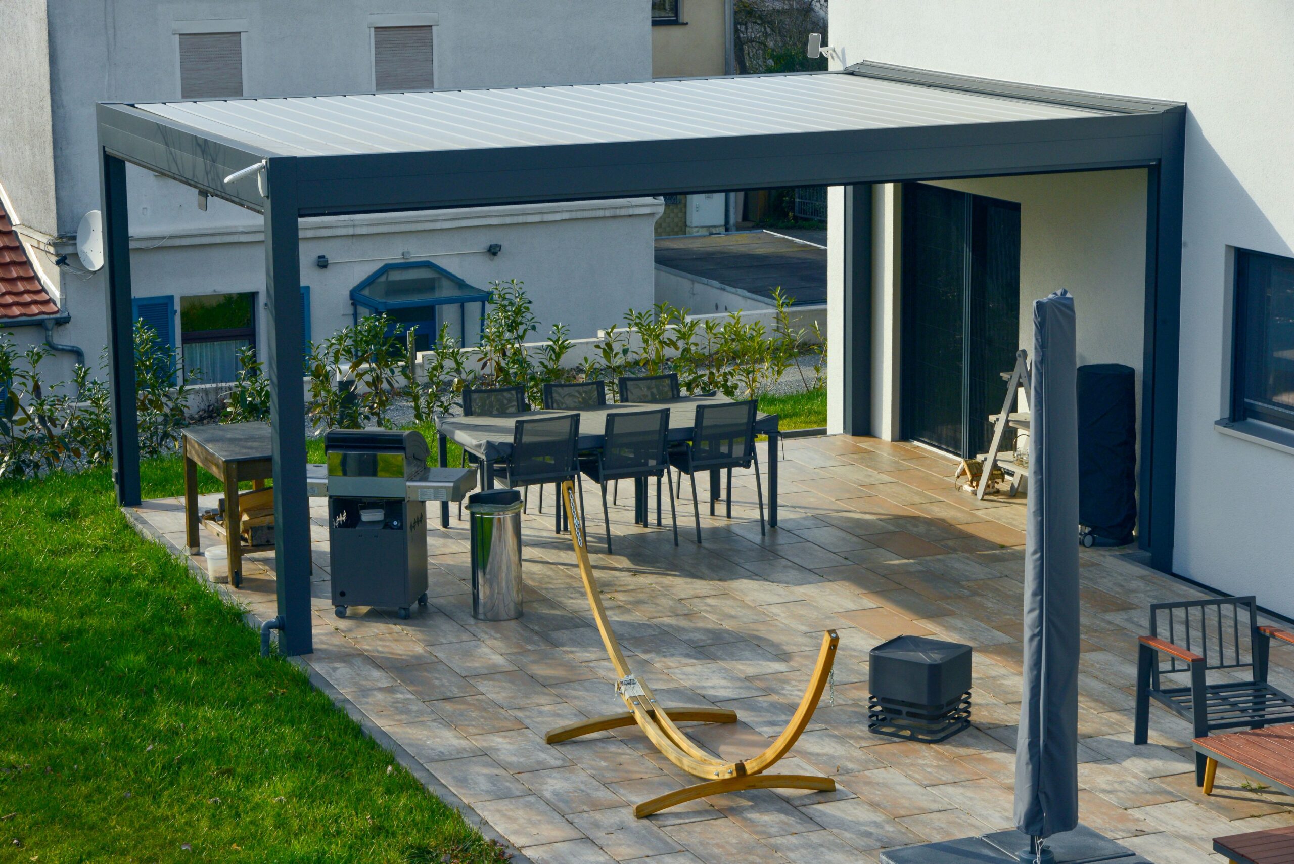 Moderne Terrassenüberdachung aus Aluminium mit klarer Linienführung über eleganter Gartenlounge